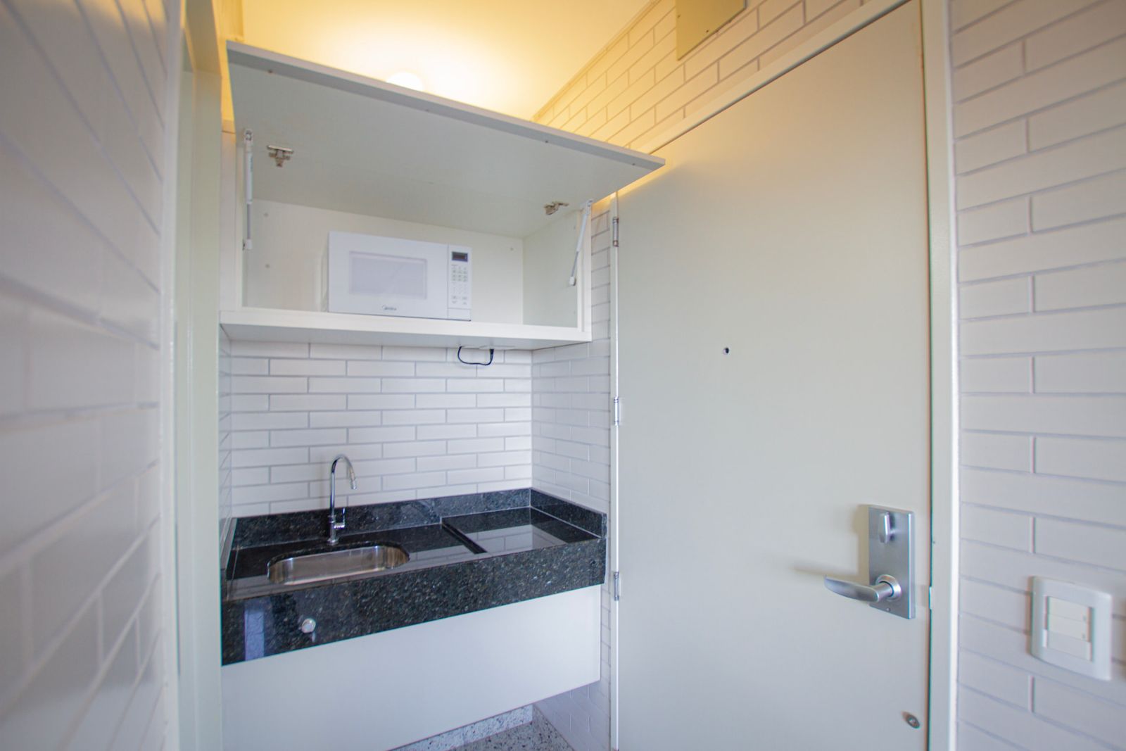 Cozinha compacta do apartamento com pia em granito e micro-ondas — Hotel Confiance Batel