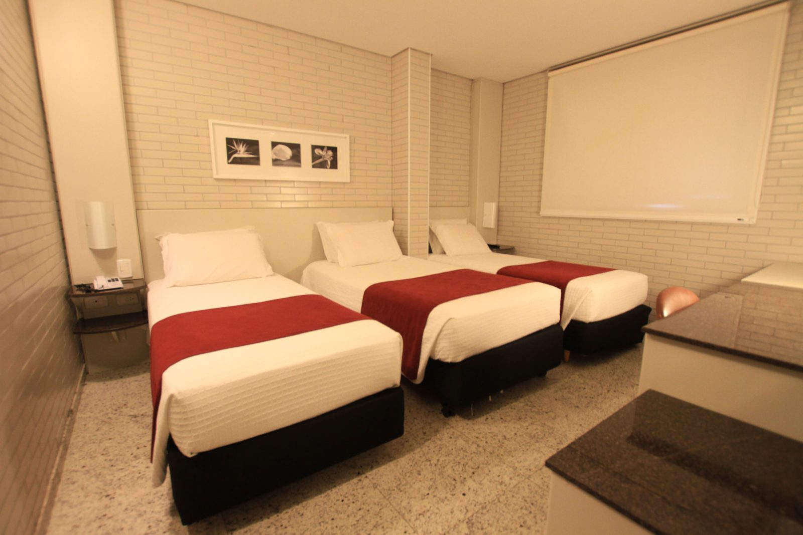 Apartamento Standard Triplo Solteiro com três camas de solteiro e parede de tijolinho branco — Hotel Confiance Batel
