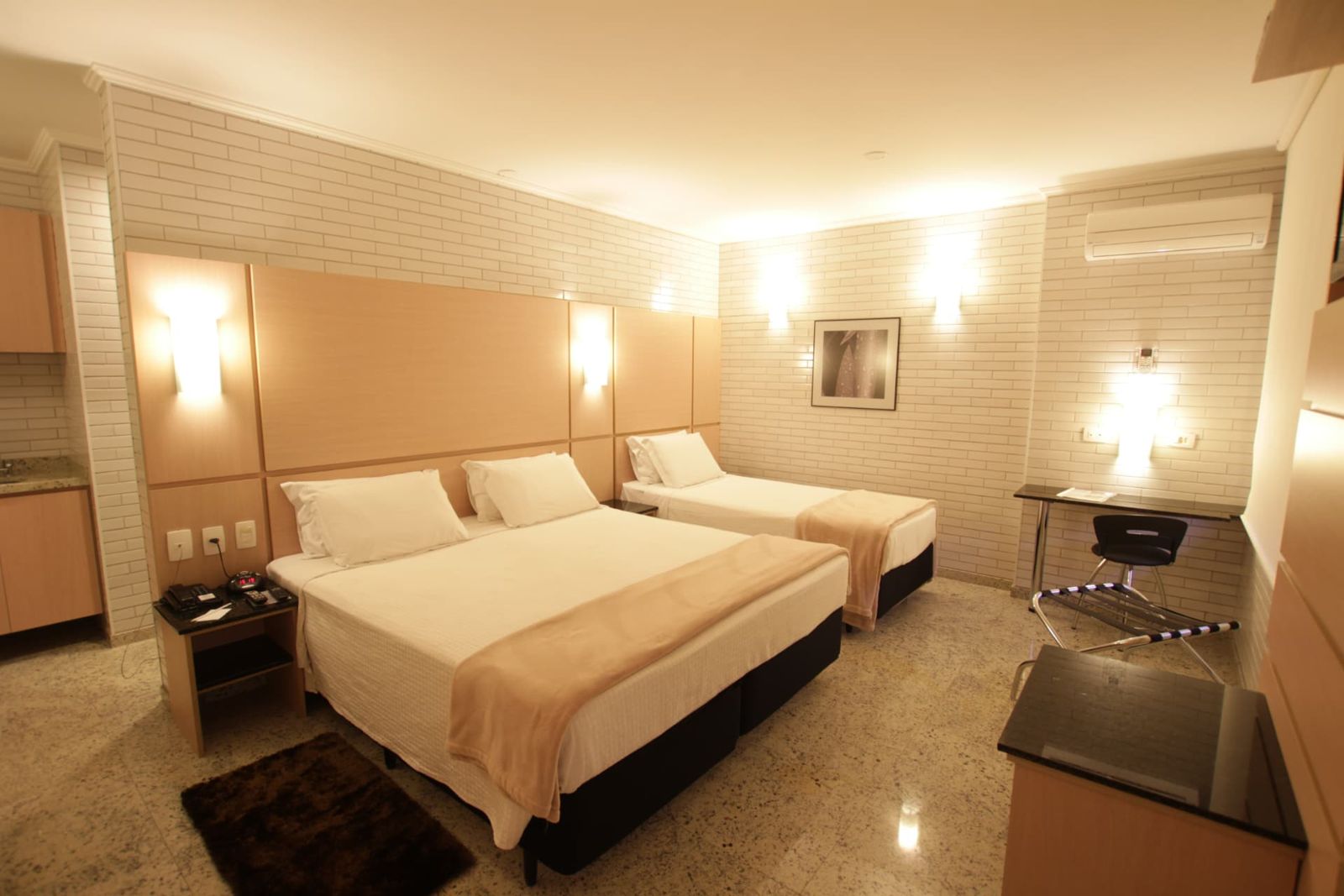 Apartamento Standard Triplo Casal com cama de casal e cama de solteiro, parede de tijolinho branco e escrivaninha — Hotel Confiance Centro Cívico