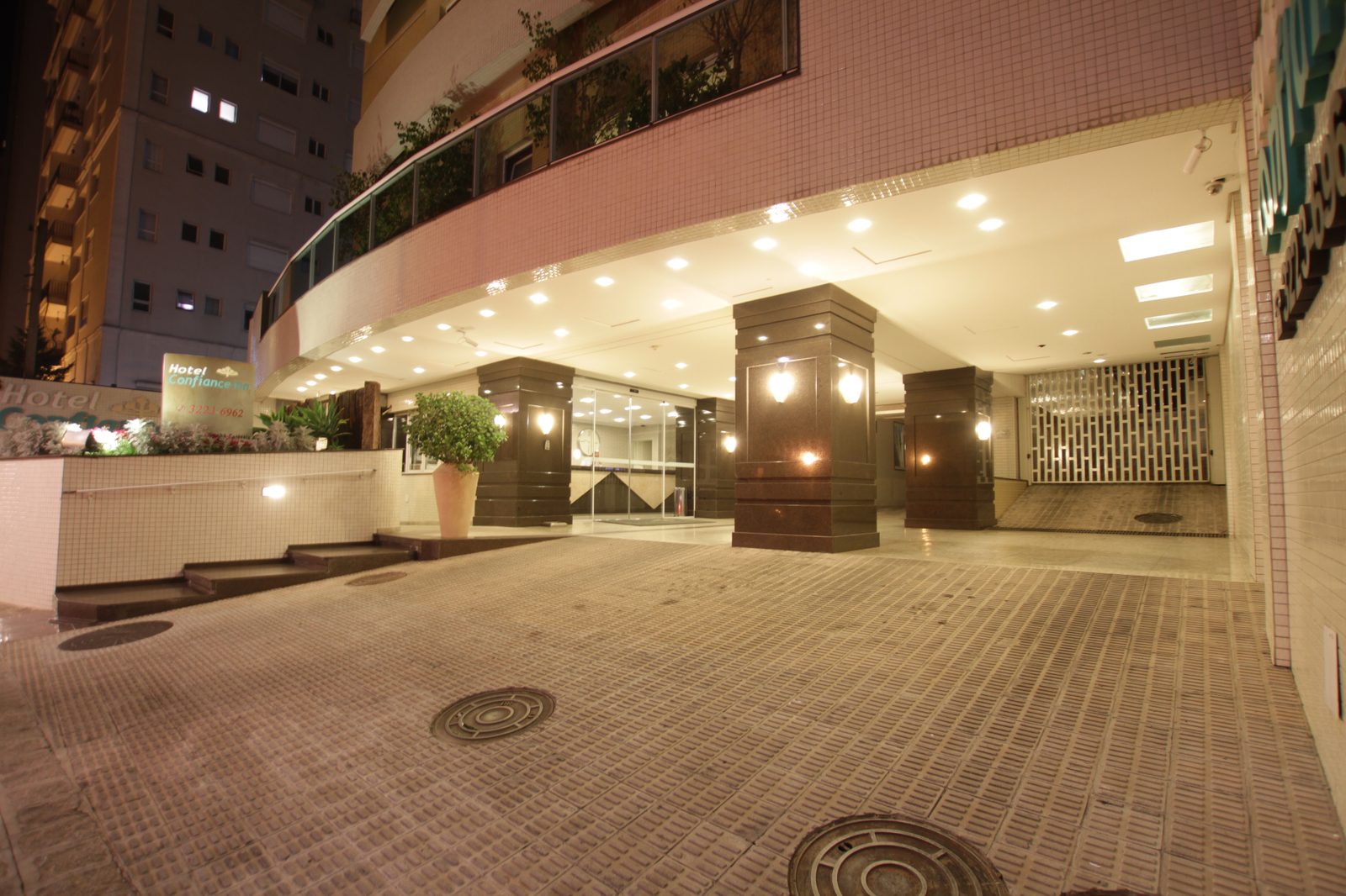 Entrada iluminada do Hotel Confiance Batel à noite